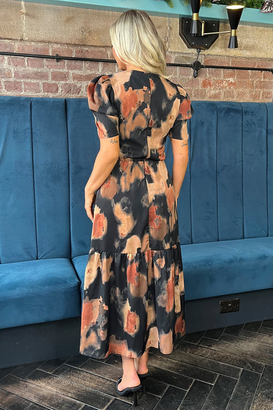 Woman wearing a patterned dress standing in front of a blue booth.