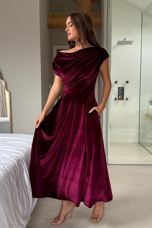 Woman wearing a burgundy satin dress in a bedroom setting