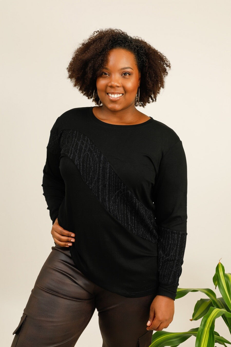 Woman wearing a black sweater with fringe details against a plain background