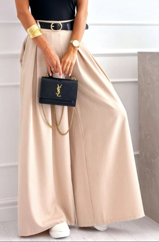 Person wearing a beige skirt and holding a black handbag with a brand logo.