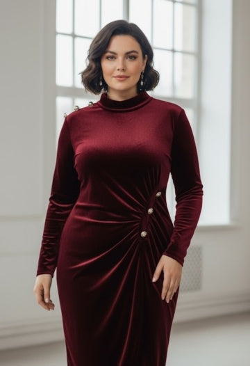 Woman wearing a burgundy velvet dress with pearl buttons in a bright room.