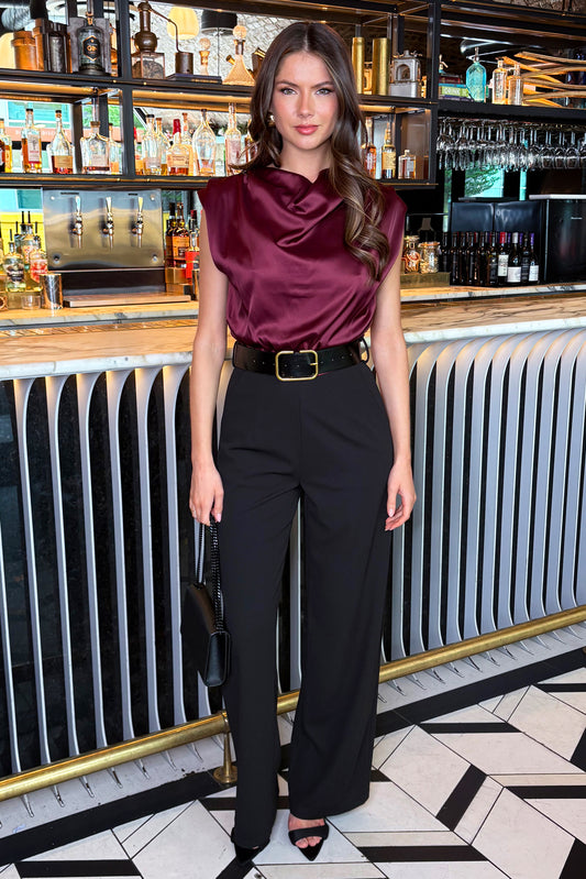 Woman in a maroon top and black pants standing in a bar setting