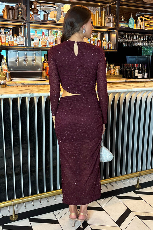Woman in a burgundy dress standing in a bar setting