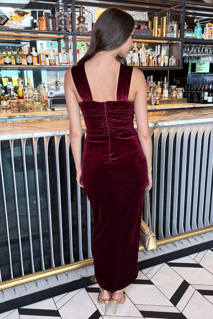 Woman in a burgundy velvet dress standing in a bar setting