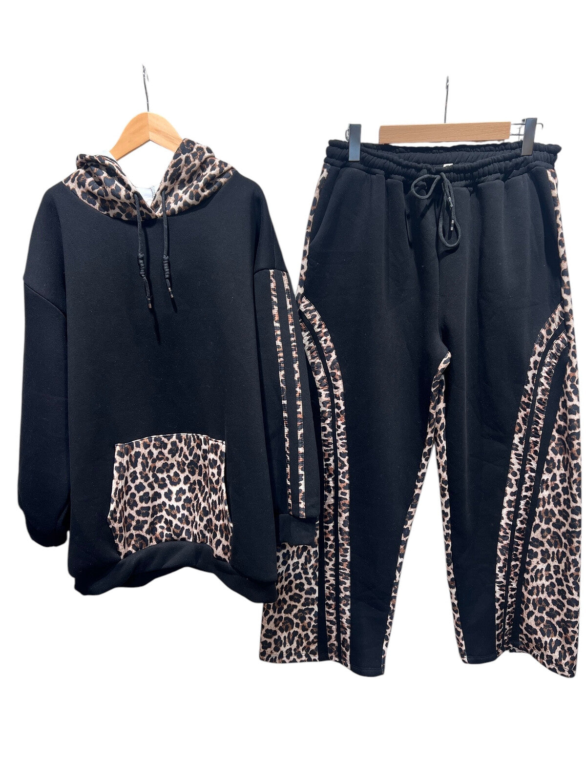 Black hoodie and pants with leopard print accents on hangers against a white background