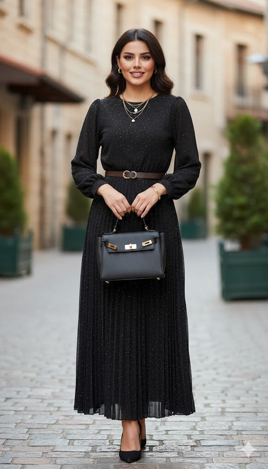 Woman in a black dress holding a black handbag on a street.