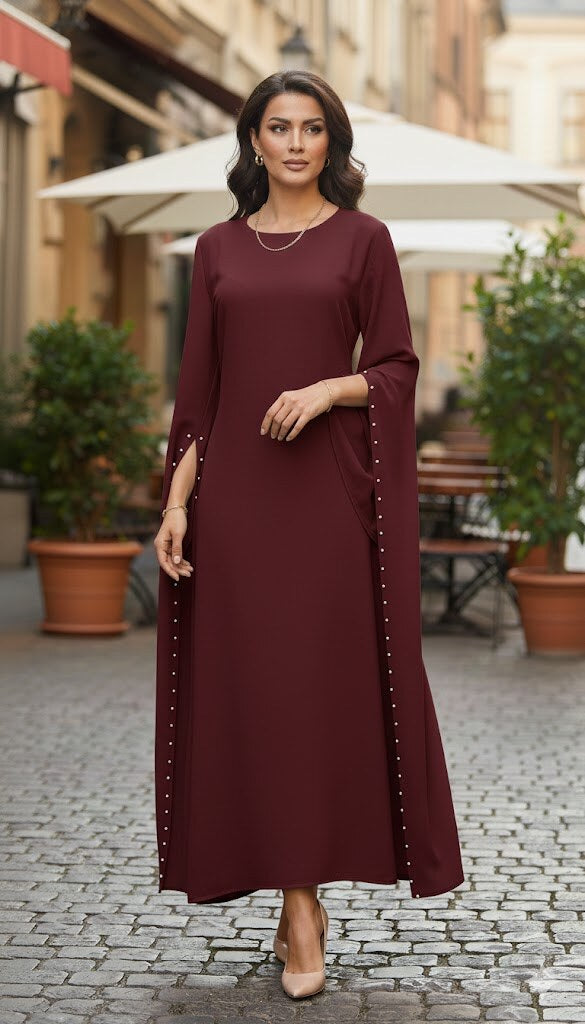 Woman in a burgundy dress standing on a street with plants and an umbrella in the background