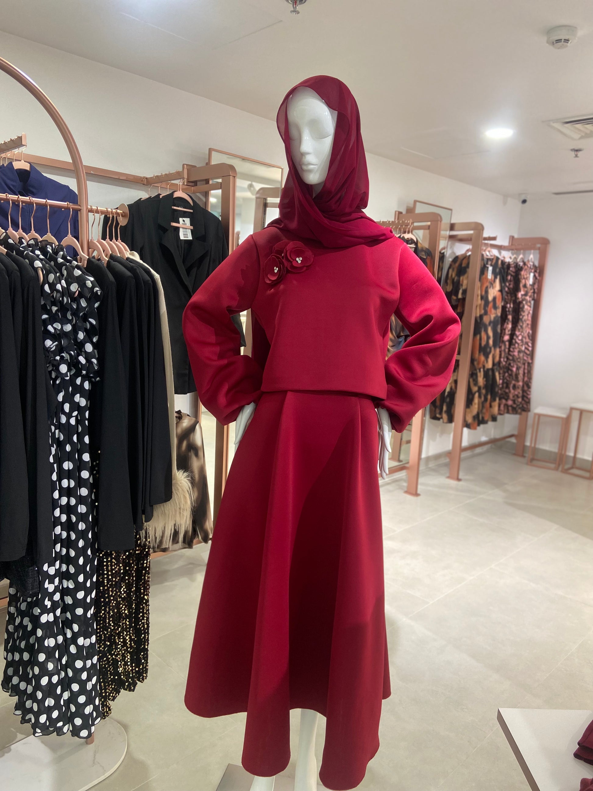 Mannequin wearing a red outfit with a hijab in a clothing store.