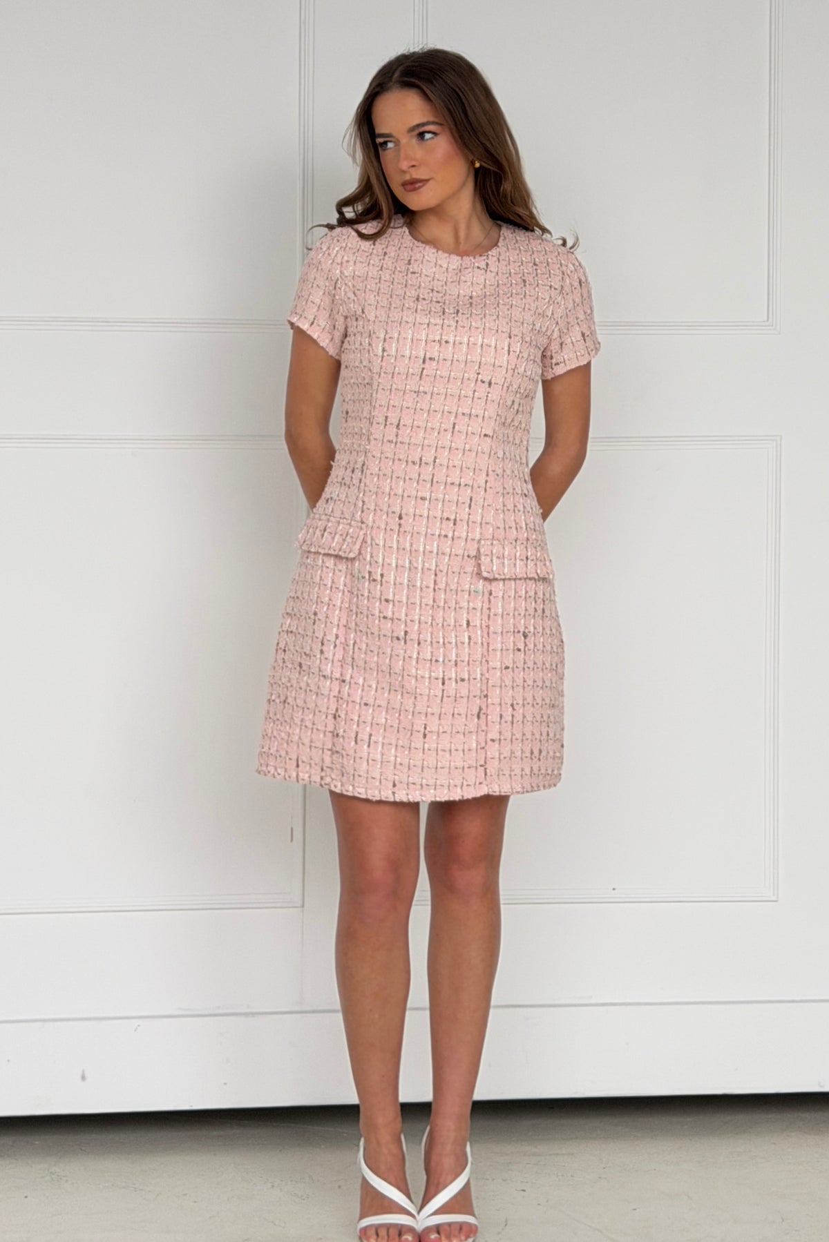 Woman wearing a pink checkered dress against a white background