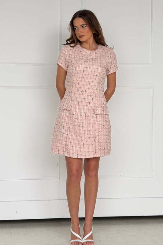 Woman wearing a pink checkered dress against a white background
