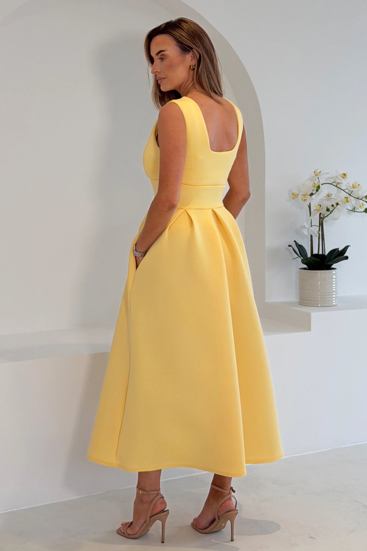 Woman wearing a yellow dress in a minimalistic setting