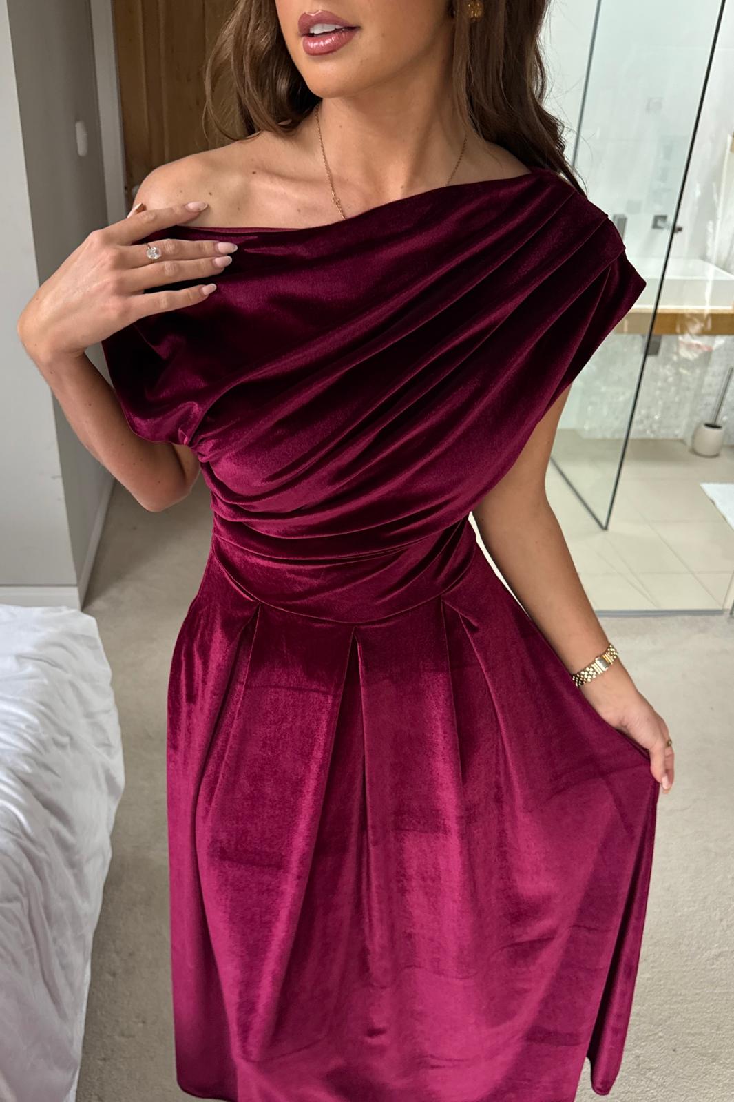 Woman wearing a burgundy off-shoulder dress indoors.