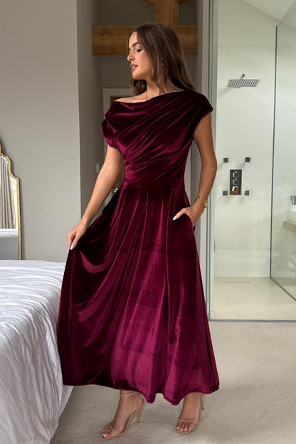 Woman wearing a burgundy satin dress in a bedroom setting