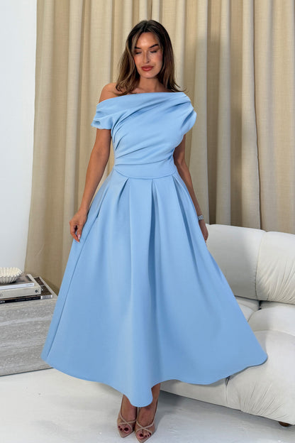 Woman wearing a light blue off-shoulder dress in a living room setting.