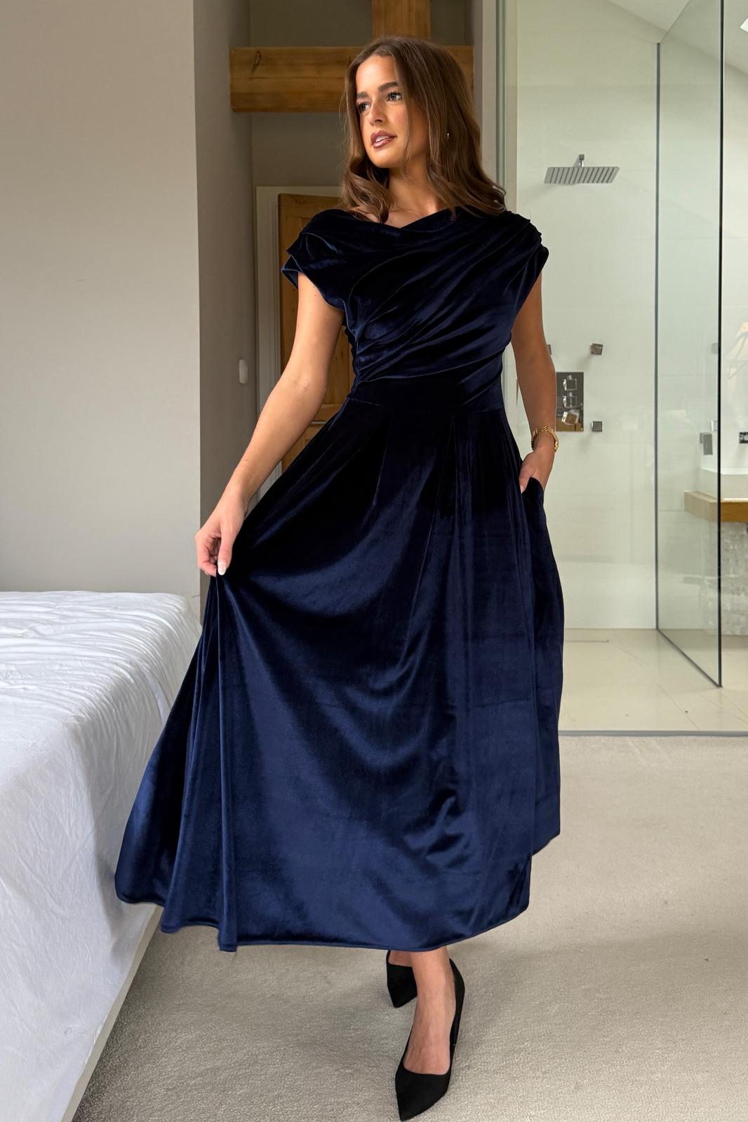 Woman wearing a navy blue dress in a bedroom setting