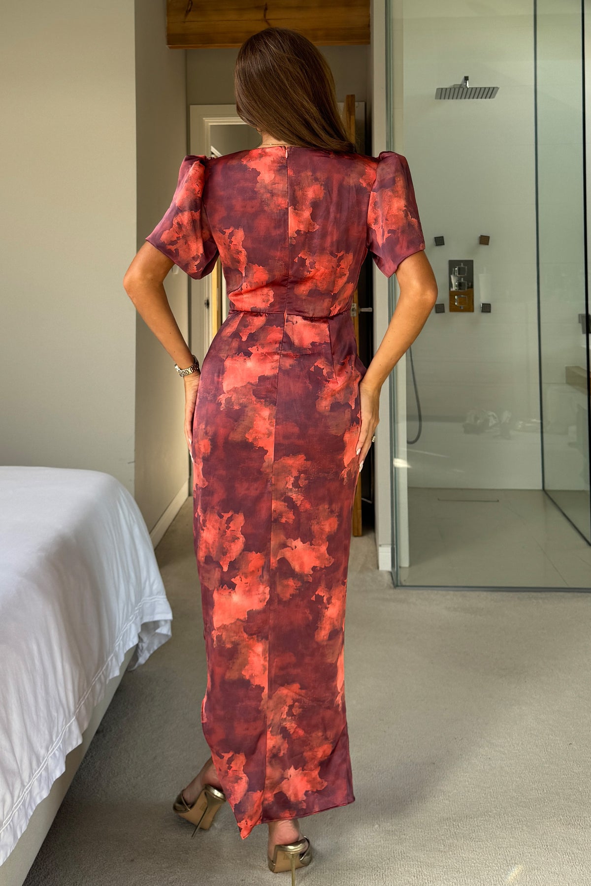 Woman wearing a red floral dress in a bedroom setting