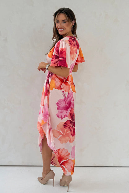 Woman wearing a colorful floral dress against a plain background