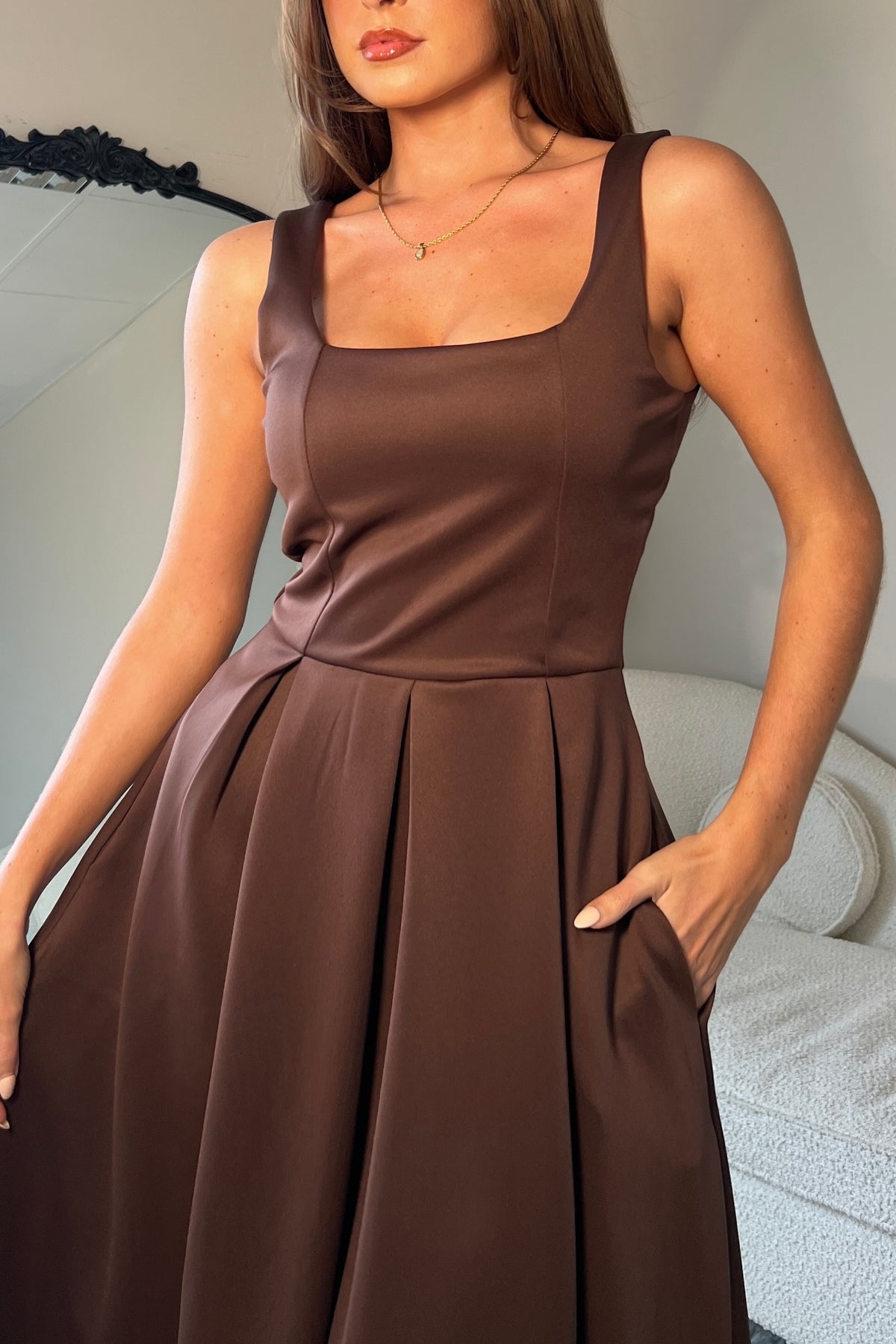 Woman wearing a brown dress with a neutral background