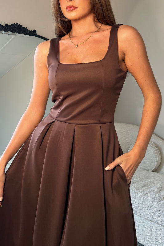 Woman wearing a brown dress with a neutral background