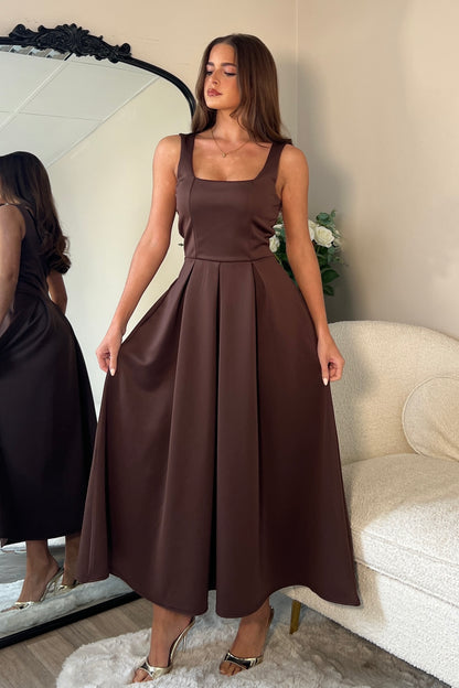 Woman wearing a brown dress standing in front of a mirror.