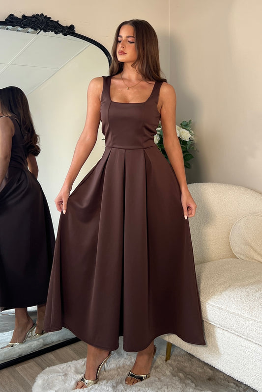 Woman wearing a brown dress standing in front of a mirror.