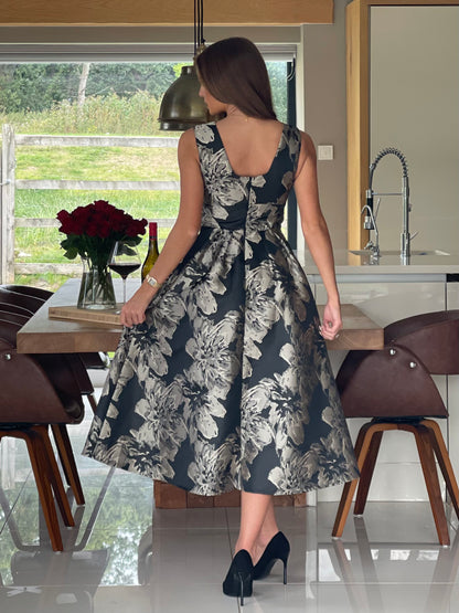 Woman in a floral dress standing in a modern kitchen.
