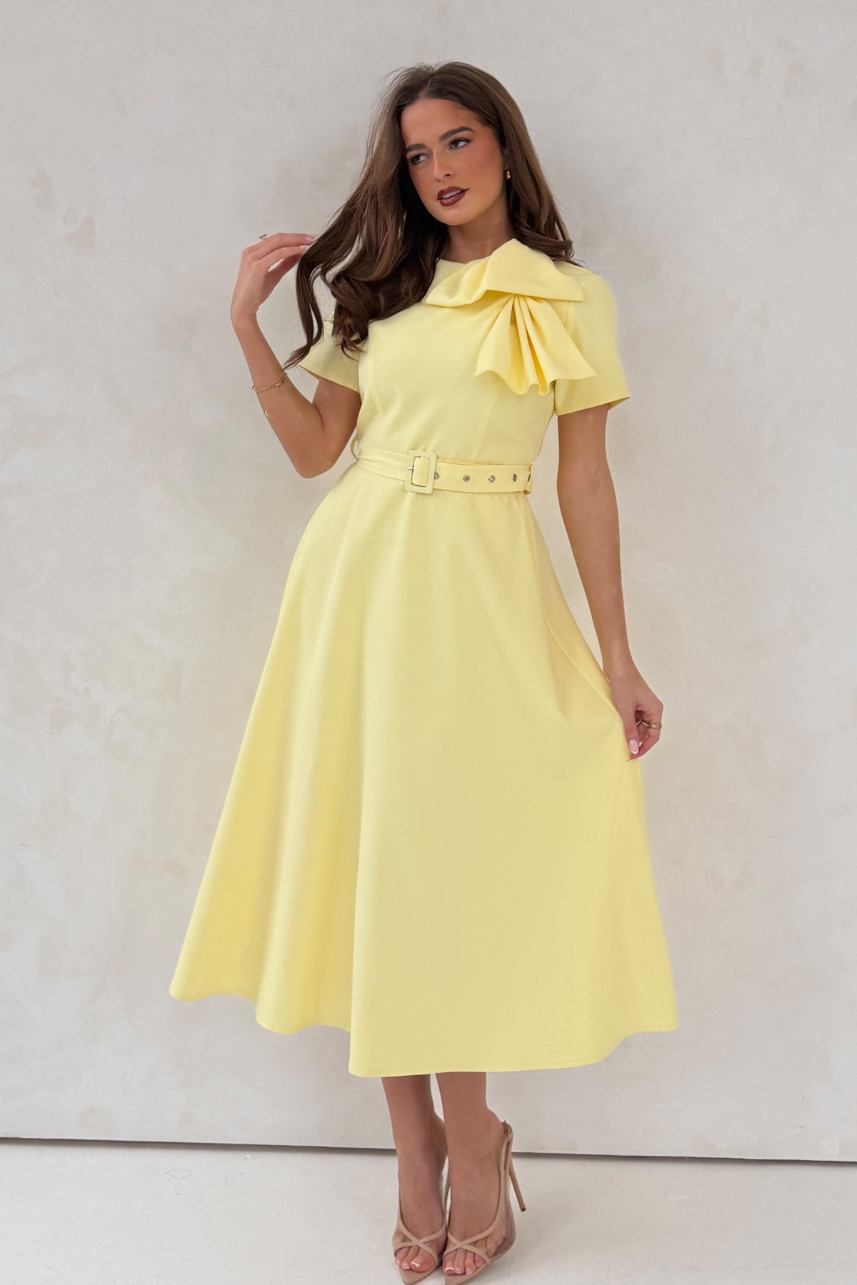 Woman wearing a yellow dress with a large bow on a white background