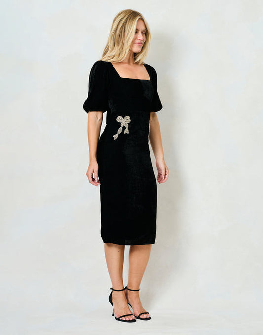 Woman wearing a black dress with a bow detail on a white background