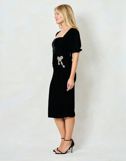 Woman wearing a black dress with a bow detail on a white background