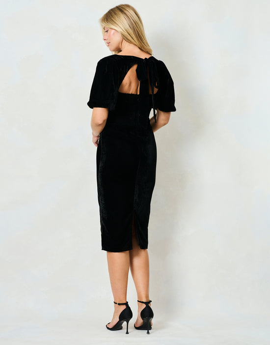 Woman wearing a black dress with cut-out back design on a white background