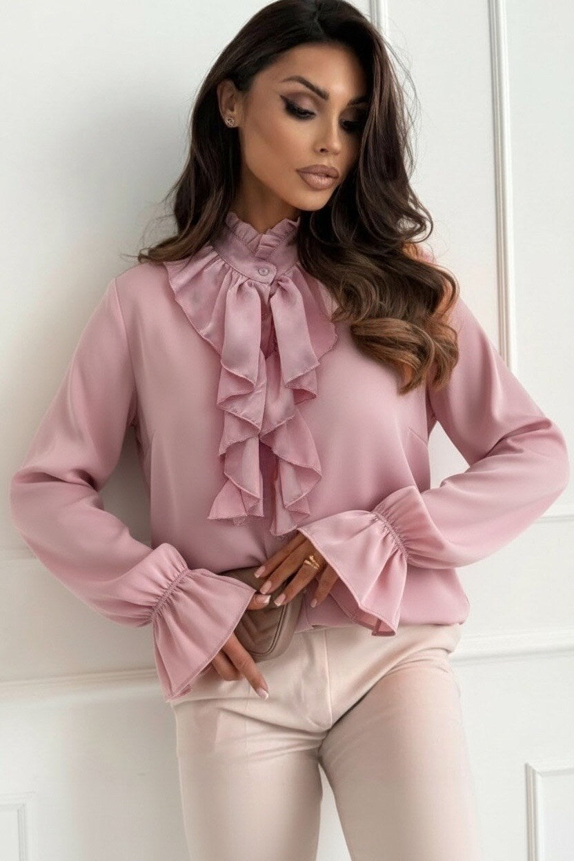 Woman wearing a pink blouse with ruffled details against a white background